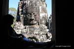 Leggendo all'ombra davanti alla faccia di pietra, Bayon, Angkor Thom, Cambogia.
