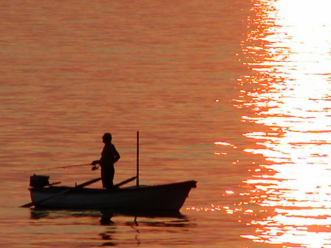 Angler nella sua barca sul mare arrossata dal sole, Starigrad, Croazia