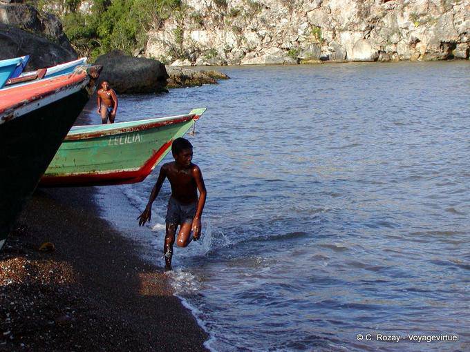 Kid in esecuzione sulla sabbia nera, Boca de Yuma, Rep. Dominicana