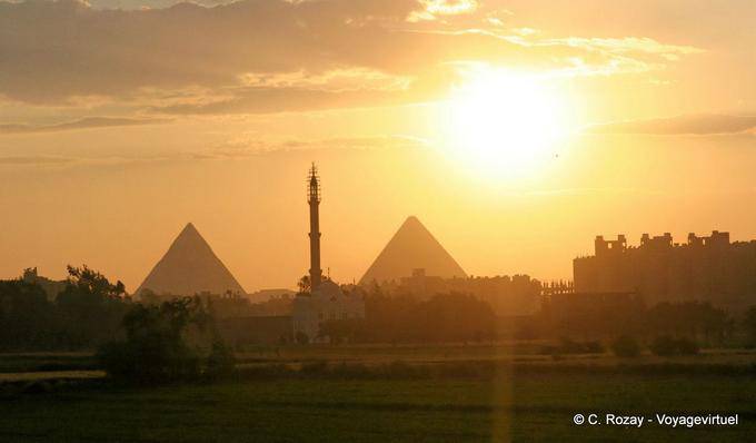 Favoloso tramonto sulle piramidi che fiancheggiano il minareto di una moschea, Cairo - Egitto