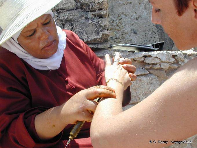 Un artista tatuaggio all'hennè officiante in prossimità dei bastioni, Essaouira - Marocco