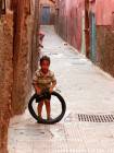Un bambino che gioca con una pista pneumatico della Medina, Marrakech, Marocco.
