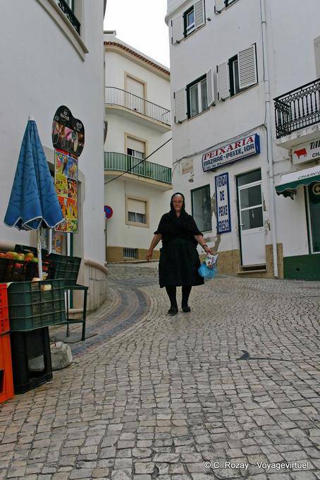 La donna in nero per la strada acciottolata, Nazaré - Portogallo