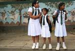 Trio di studentesse in uniforme davanti ad un murale, Kandy, Ceylon Sri Lanka.